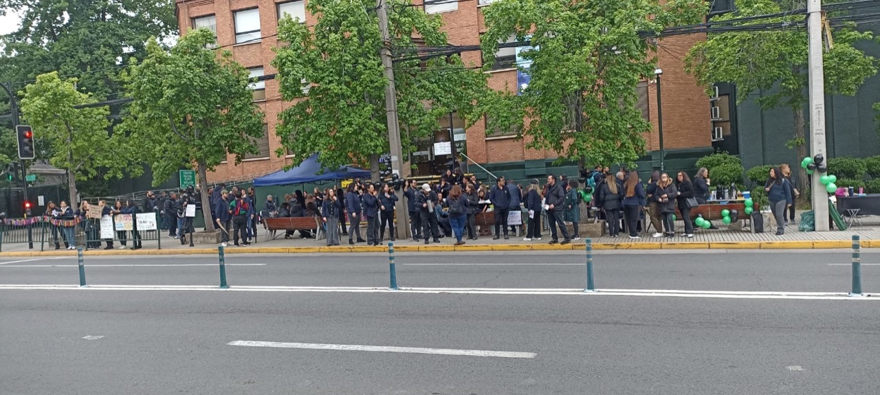 Trabajadores reunidos frente al Colegio Bradford durante el inicio de la huelga, con carteles y globos verdes y negros.